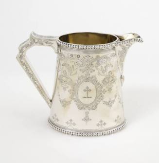 A Victorian sterling silver cream pitcher with a finely engraved cartouche depicting a heraldic…