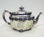 A sterling silver teapot with four clawed-feet and floral gadrooning around the waist and edge …