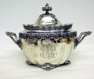 A sterling silver sugar bowl with four clawed-feet, two handles, and floral gadrooning around t…