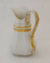 A back view of the cream pitcher showcasing the handle. 