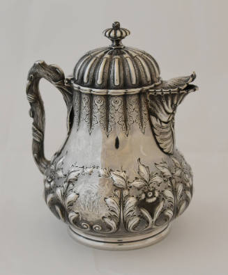 A silver chocolate pot with a hinged lid decorated with fluted and repousse foliage. The handle…