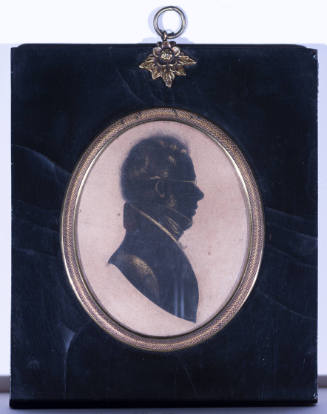 A drawn silhouette of a man in profile in an oval gilt frame with a lacquered wooden panel fram…