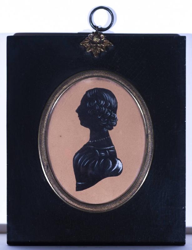 A drawn silhouette of a woman in profile in an oval gilt frame with a lacquered wooden panel fr…