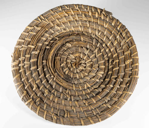 A rice fanner basket made from native wire grass and reeds in a spiral pattern.