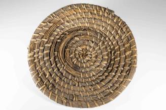 A rice fanner basket made from native wire grass and reeds in a spiral pattern.