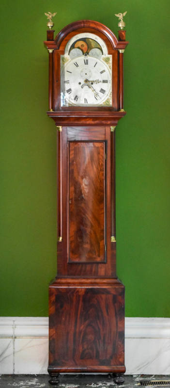 A mahogany tall case clock with an arched bonnet with two brass eagle finials on box plinths ab…