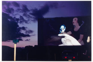 A drive-in movie theater screen with a still of an animated Snow White and blue bird set agains…