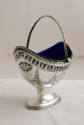 A silver oval sugar basket on a pedestal base with a cobalt blue glass liner.