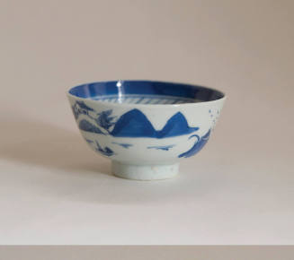 A porcelain teacup with no handle from a set of dinnerware featuring blue and white Chinese lan…