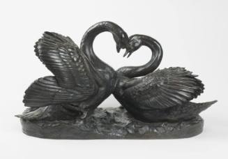 A bronze sculpture of two swans facing one another.
