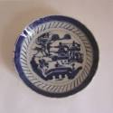A porcelain saucer from a set of dinnerware featuring blue and white Chinese landscapes.
