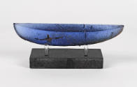 A blue glass boat-shaped sculpture mounted above a black platform.