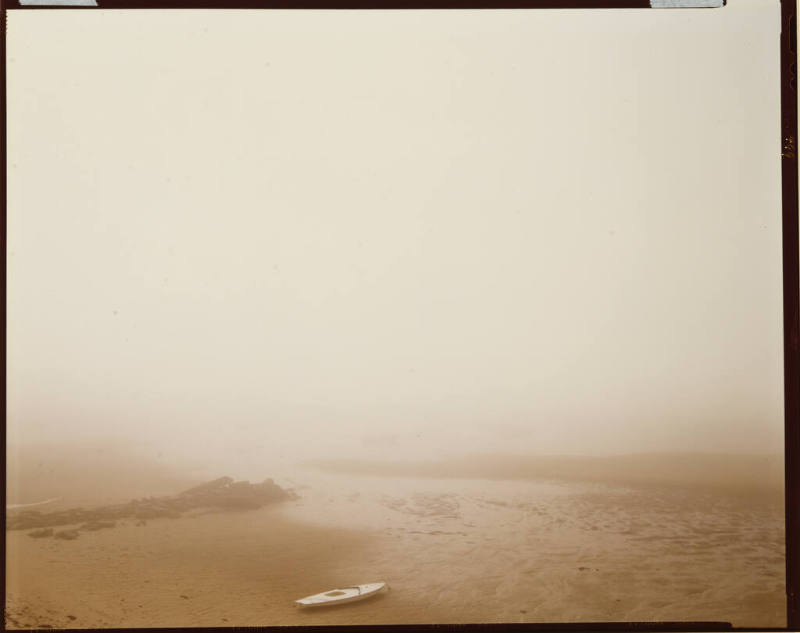 Misty landscape of a lone boat stranded on the sand during a low tide.