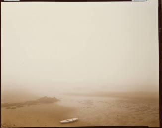 Misty landscape of a lone boat stranded on the sand during a low tide.