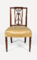 A frontal view of a mahogany side chair with a gold upholstered seat and lyre-style back.