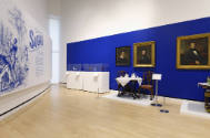 The northeast corner of the gallery featuring the title wall on the left and two vitrines of de…