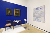 The southeast corner of the gallery with a text panel on the right wall and the final tea servi…