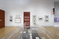 An installation shot of the "New York City" text panel with a set of photographs on either side…