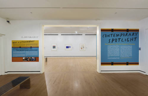 An installation shot of the title wall and explanatory lithography text panel on either side of…