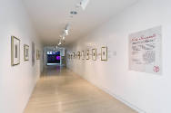 An installation shot of the title panel and the corridor hung with prints. 