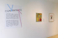 An installation shot of the west wall with the title panel on the left and two works of art to …