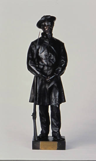 A bronze sculpture of a man in uniform, with crumpled hat, hands folded in front of him, and a …