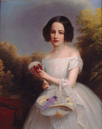 A three-quarter length portrait of a young girl with her hat on her arm, wearing a white dress.…