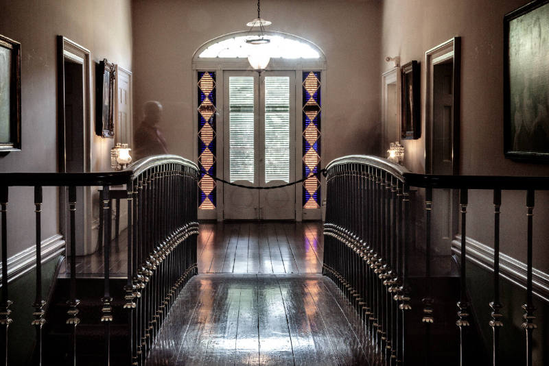 A color photograph of blurred visitors captured as they walk across the second-floor landing by…