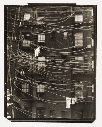 A black and white photograph of laundry hung on telephone wires.