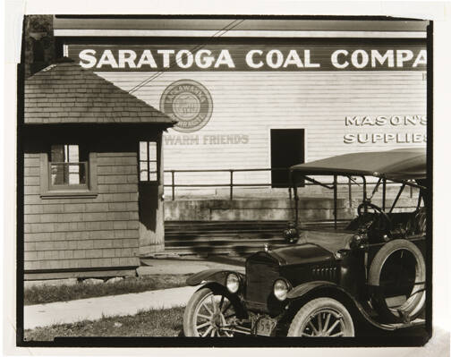A black and white photograph of a car in front of the Saratoga Coal Company building.