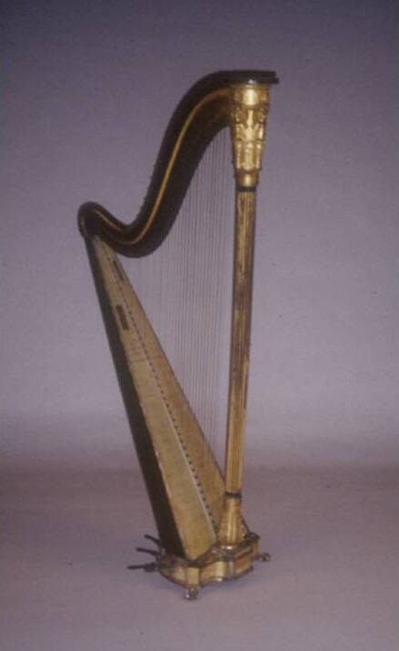 A gilded harp with reeded central column, neoclassical angels and cherubs beneath the crown, an…