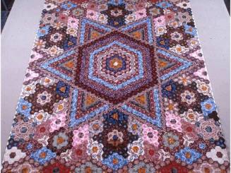A pieced mosaic quilt with a central motif of a six-pointed star, surrounded by various star, d…