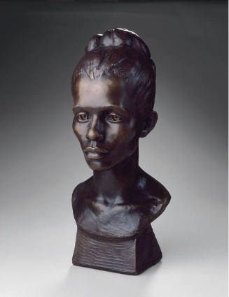 A bust of young female with her hair pulled into a bun on the back of her head.