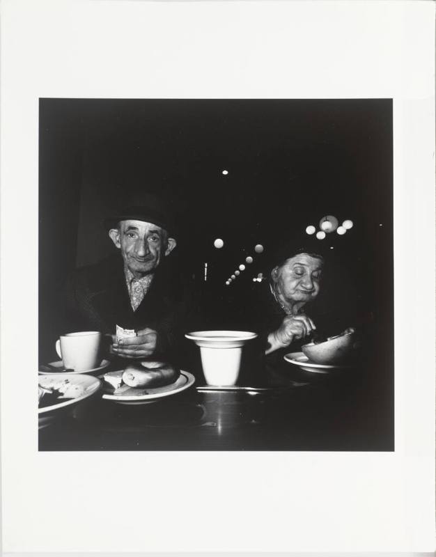 A black and white photograph of an older man looking at the camera holding a wad of money in hi…