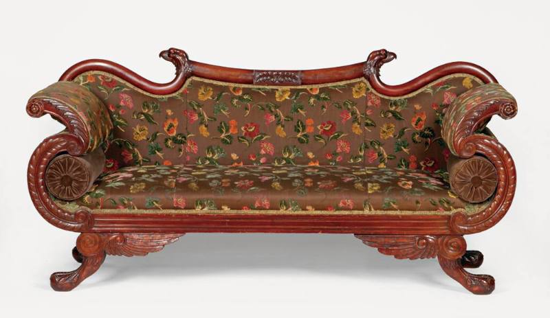 A carved mahogany sofa featuring American eagle details, including carved heads on each corner …