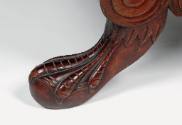 A detail of the carved mahogany eagle webbed claw foot with wings.