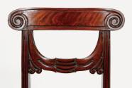 A detail of the carved mahogany tablet crest rail with volute or swirl ends.