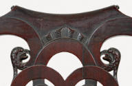 A detail of the center crest rail and carved bird's head on the back splat. 