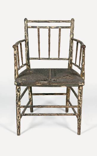 A painted wooden armchair composed of bamboo-style spindles and supports with a woven rush seat…
