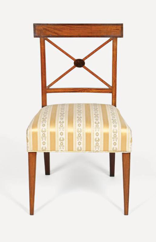 A side chair with a X-shaped cross bar and an upholstered seat in green with gold stripes. 