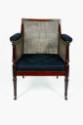 A mahogany armchair with caned back, sides, and seat supported by turned legs on casters. The a…