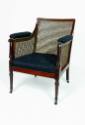 A mahogany armchair with caned back, sides, and seat supported by turned legs on casters. The a…