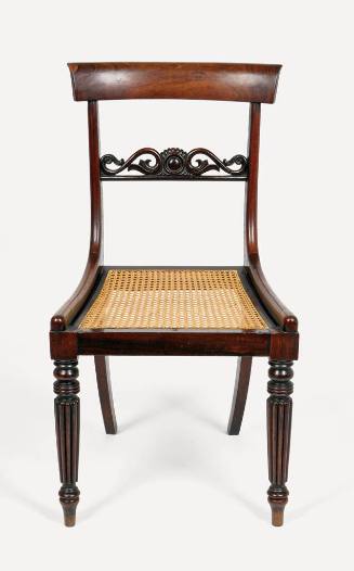 One of six rosewood side chairs with caned seats, a central carved back splat, and reeded legs.