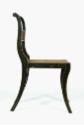 A side view of a black and gold fancy painted side chair with reeded crest rail and caned seat.