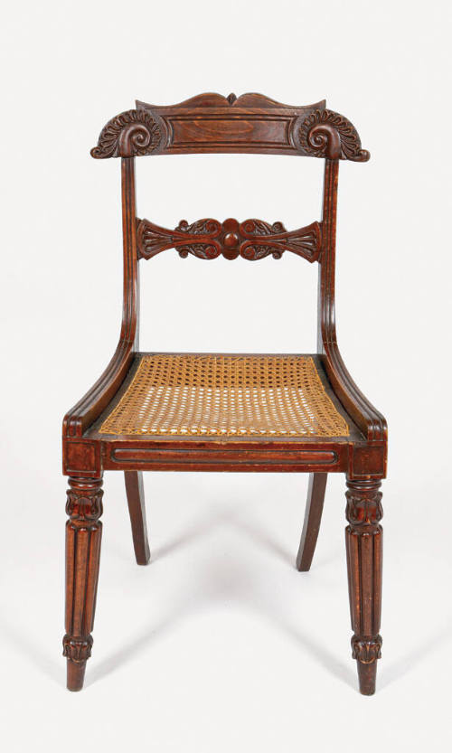 One of four English pine side chairs with a caned seat, reeded legs, and carved back splat and …