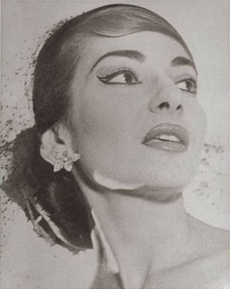 A black and white image of opera singer Maria Callas with large floral earrings and netted veil…