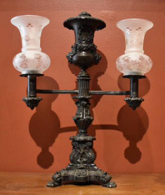 A bronze argand lamp with two arms and two reproduction frosted chimneys.