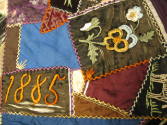 A detail of a patch embroidered with the date and another with pansy flowers. 