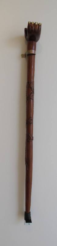 A carved cedar walking stick with a hand and an alligator.