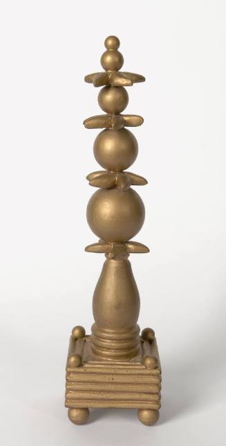 A golden sculpture composed of stacked spheres with horizontal star-like shapes in between.